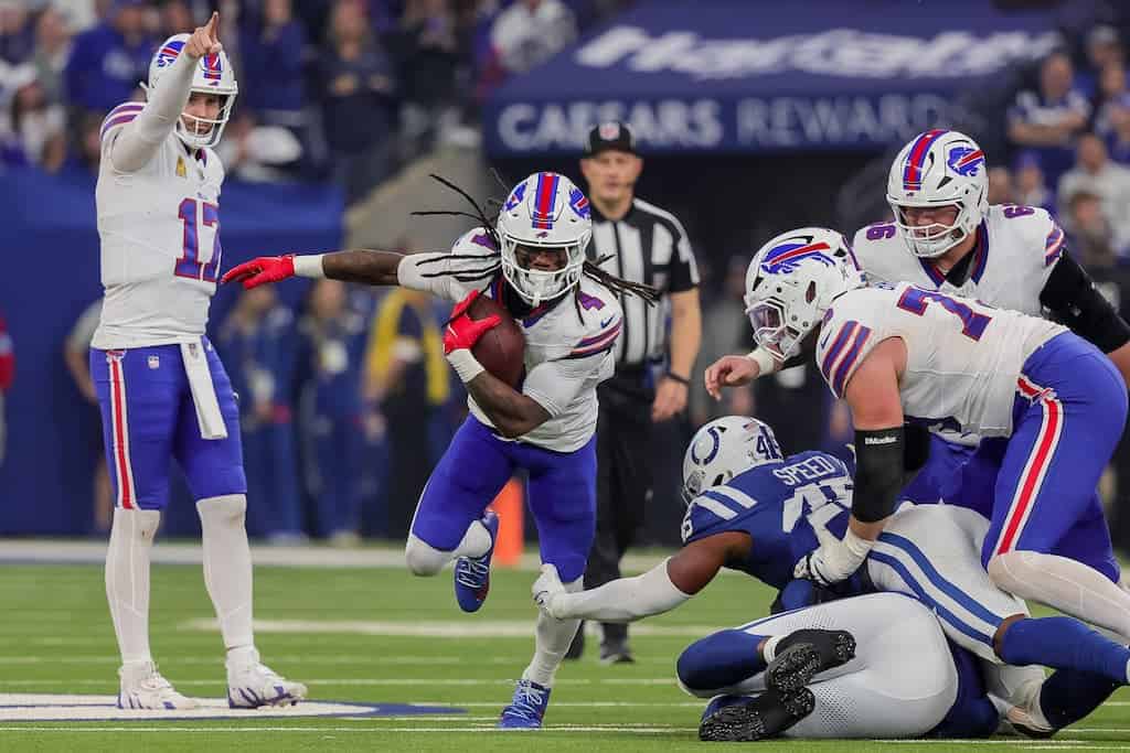 Quarterback Josh Allen pointing downfield as his running back breaks a huge run.