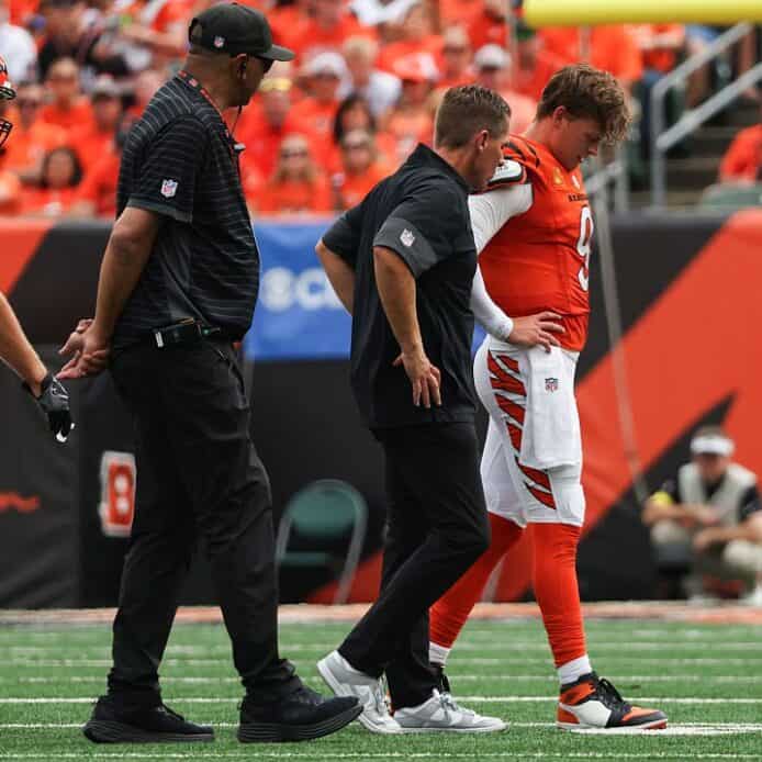 Injury consultation during an NFL game featuring Cincinnati Bengals players.