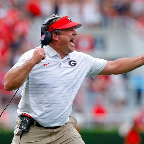 Excited football coach on the sideline during game celebrating success.
