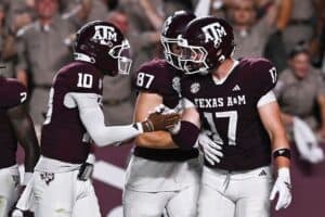Aggressive Texas A&M football team celebrating on the field after a successful play.