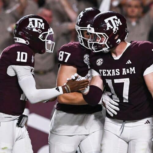 Aggressive Texas A&M football team celebrating on the field after a successful play.